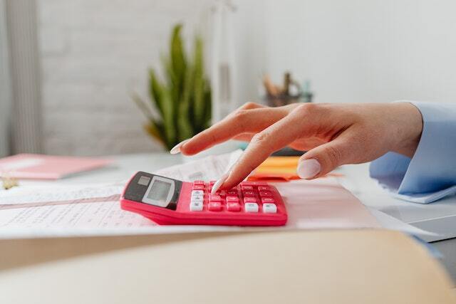 close-up of hand punching in numbers on a pink calculator